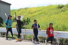 2026年の武者修行：緑の土手のそばで手を振る参加者たち